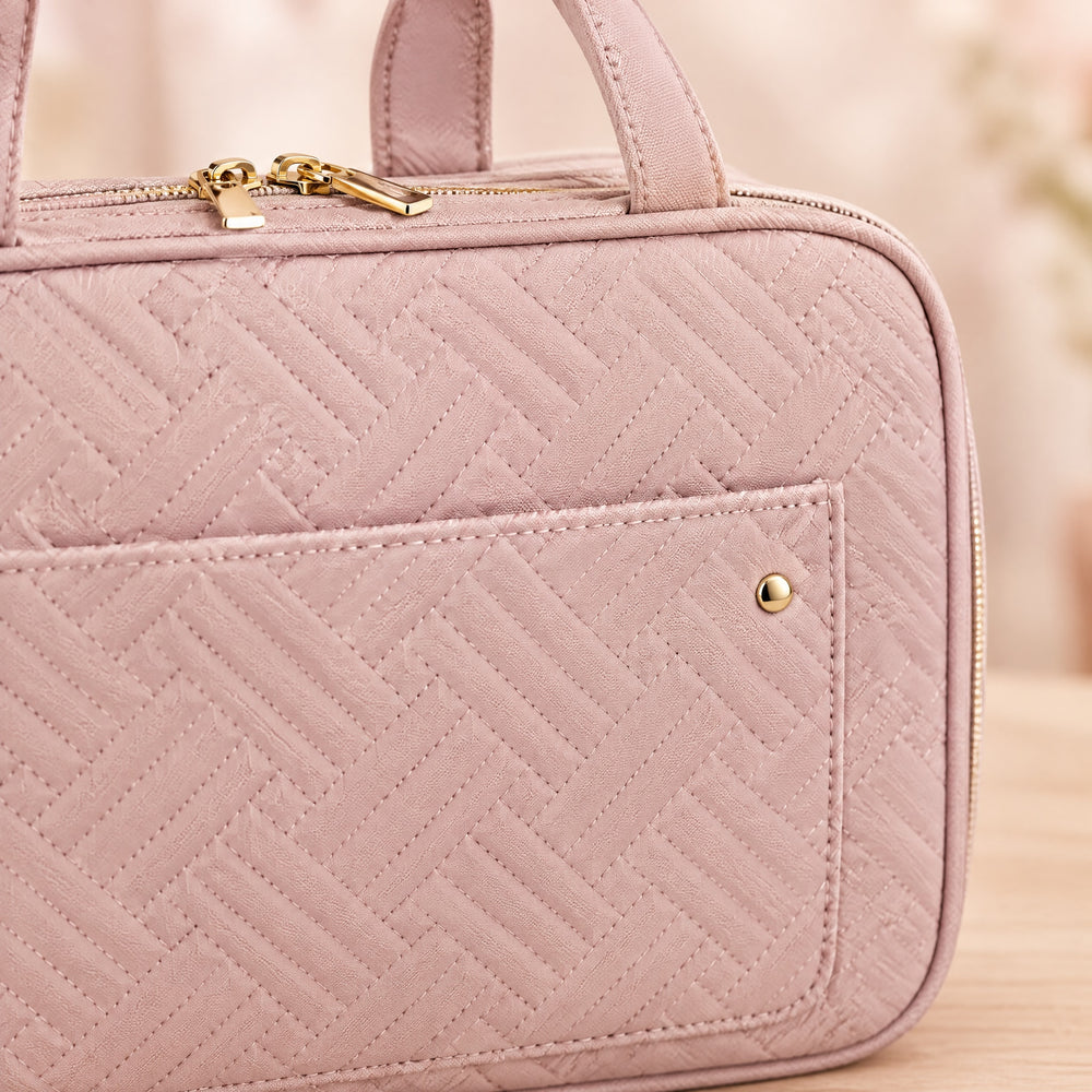 RosyIron toiletry bag close-up of pink quilted fabric, gold zipper pulls and front pocket snap
