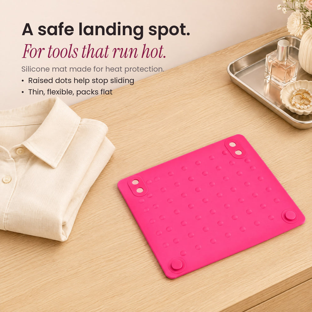 RosyIron pink silicone heat-resistant mat on a wood vanity next to a folded cream shirt and silver tray