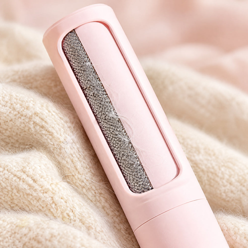 RosyIron lint brush close-up showing the grey woven fabric pad holding fine hairs over a cream knit sweater