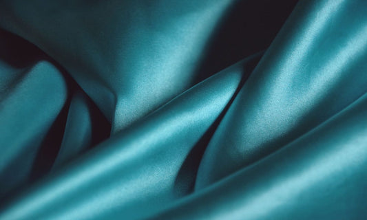 Soft folds of smooth teal silk satin fabric