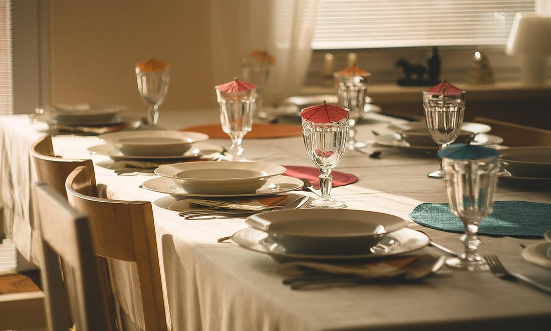Dining table laid with a white tablecloth, plates and glasses in warm afternoon light