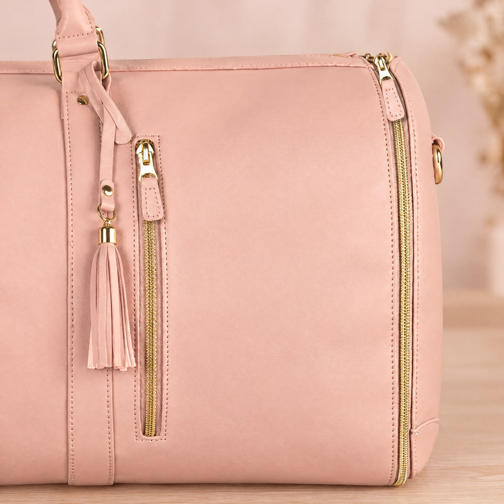 RosyIron garment duffel close-up of pink PU, gold zipper front pocket, D-ring handle and leather tassel