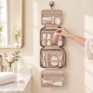 RosyIron pink hanging toiletry bag unfolded on a bathroom wall hook with toiletries in clear pockets