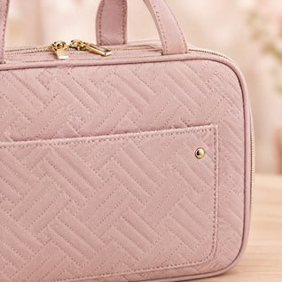 RosyIron toiletry bag close-up of pink quilted fabric, gold zipper pulls and front pocket snap