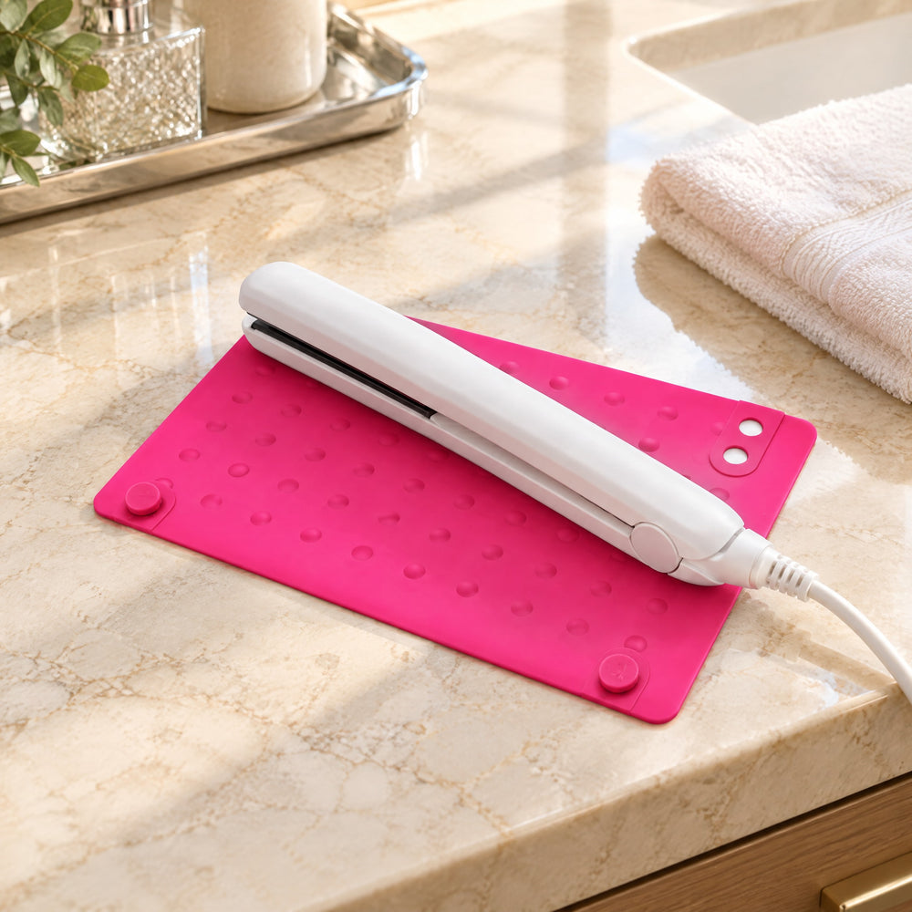 RosyIron pink silicone heat-resistant mat on a marble hotel vanity with a white hair straightener resting on it