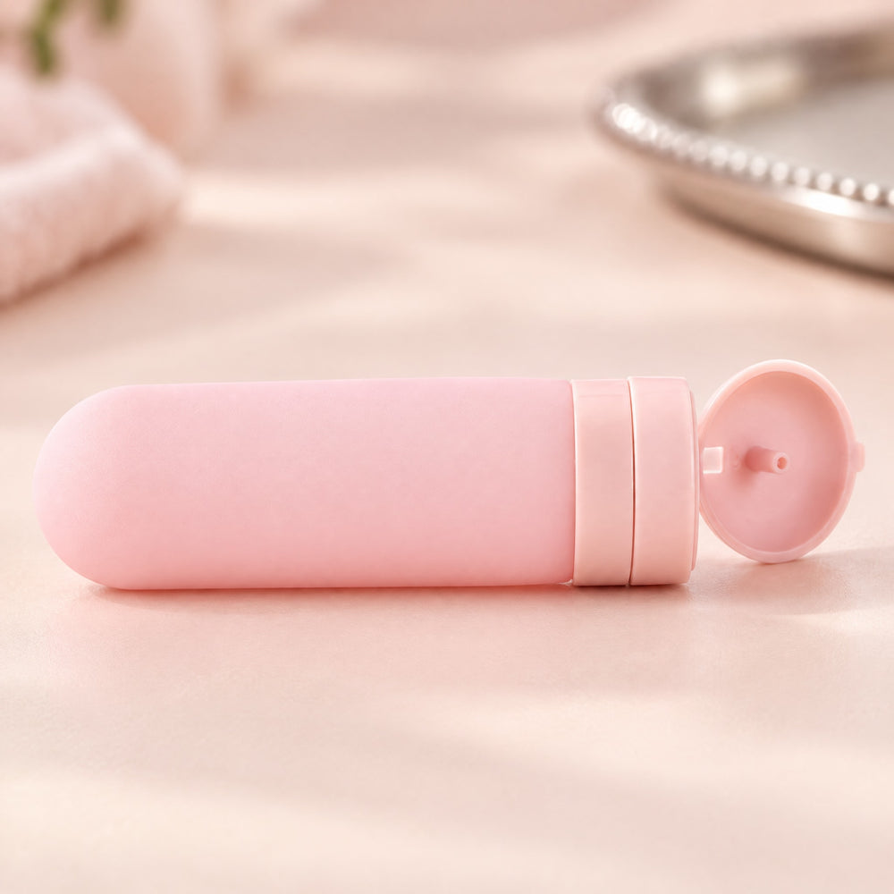 RosyIron pink silicone travel bottle close-up with the flip-top cap open on a blush surface