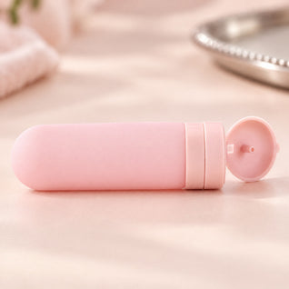RosyIron pink silicone travel bottle close-up with the flip-top cap open on a blush surface