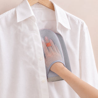 RosyIron steamer glove worn on a hand inside a hanging white dress shirt as a pressing surface