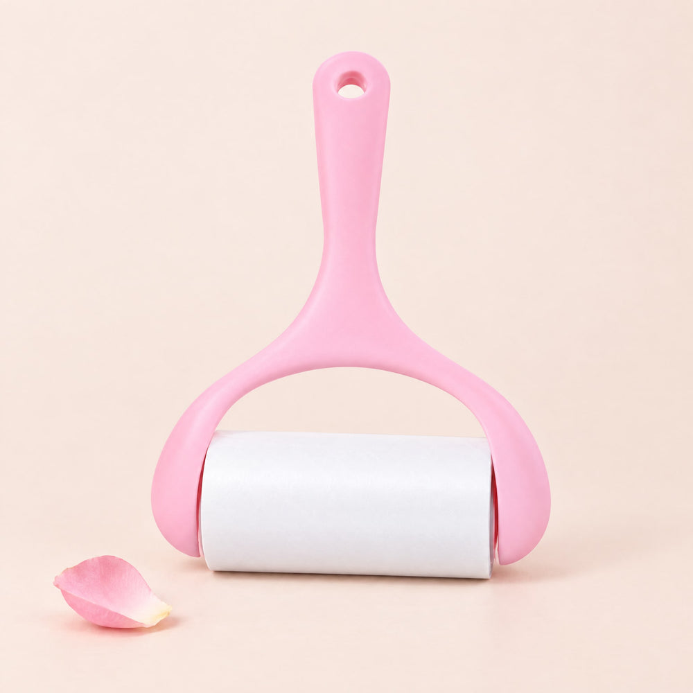 RosyIron sticky lint roller with pink handle and white paper roll on a blush-cream backdrop