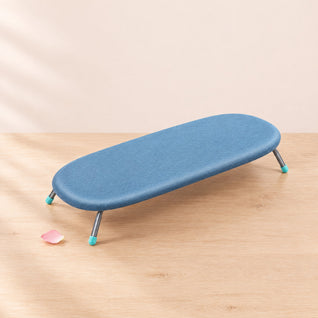 RosyIron folding tabletop ironing board with blue cover open on a light wood table