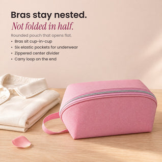 RosyIron travel lingerie bag in pink beside a folded cream shirt on a light wood surface