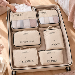 RosyIron cream packing cubes laid flat in an open suitcase while hands add a folded white shirt