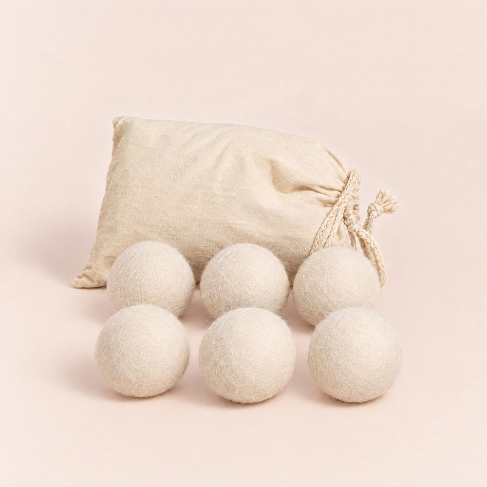 RosyIron wool dryer balls, six cream-white felted wool balls in front of a cotton drawstring bag